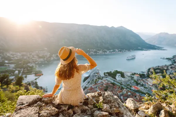Bir kayanın üzerindeki genç bir kadın körfezin manzarasından hoşlanıyor. Şapkalı bir turist kendini özgür hisseder ve bacaklarını sallayarak gözlem güvertesinde eğlenir. Turizm, doğa ve güzellik kavramı.