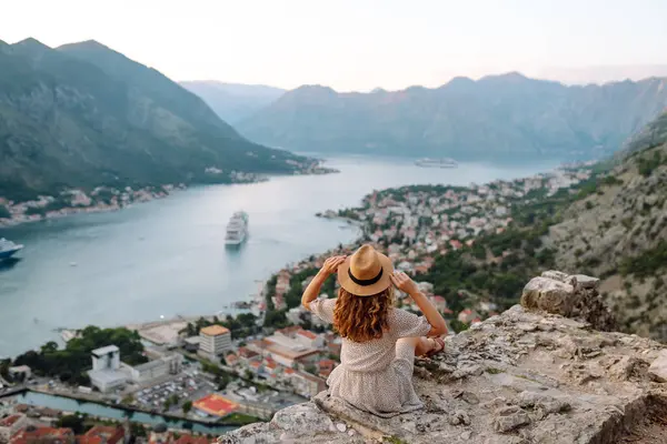 Bir kayanın üzerindeki genç bir kadın körfezin manzarasından hoşlanıyor. Şapkalı bir turist kendini özgür hisseder ve bacaklarını sallayarak gözlem güvertesinde eğlenir. Turizm, doğa ve güzellik kavramı.