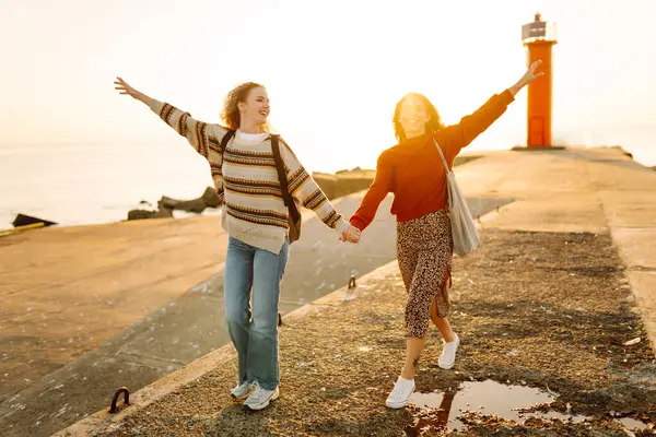Kız arkadaşlar iskelede yürüyor ve gün batımında birlikte eğleniyorlar. İki genç kadın birlikte vakit geçiriyorlar, deniz manzarası ve yolculuğun tadını çıkarıyorlar. Arkadaşlık kavramı, eğlence..