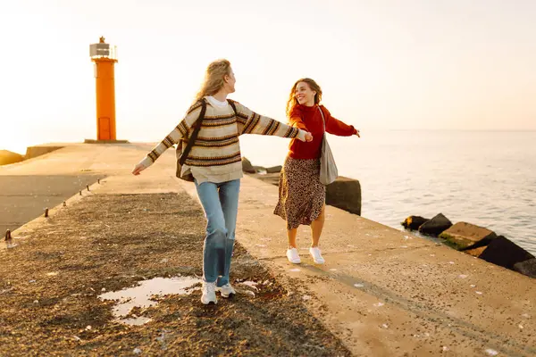 Kız arkadaşlar iskelede yürüyor ve gün batımında birlikte eğleniyorlar. İki genç kadın birlikte vakit geçiriyorlar, deniz manzarası ve yolculuğun tadını çıkarıyorlar. Arkadaşlık kavramı, eğlence..
