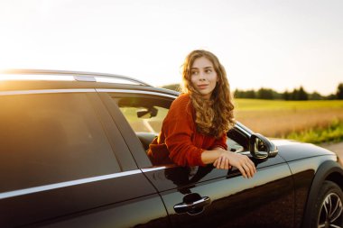 Seyahat tutkusu. Pencereden sarkan şapkalı mutlu bir gezgin. Gün batımında özgürlük hisseden genç bir kadın. Macera konsepti.