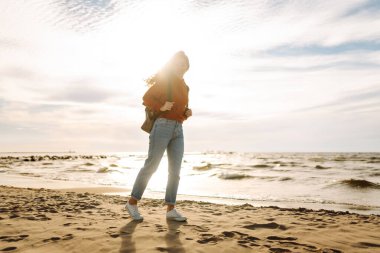 Sırt çantalı gezgin gün batımında sahilde duruyor, özgürlüğü hissediyor. Genç bir kadın kumsalda yürüyor, deniz manzarasının tadını çıkarıyor. Zevk kavramı, özgürlük..