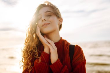 Sırt çantalı gezgin gün batımında sahilde duruyor, özgürlüğü hissediyor. Genç bir kadın kumsalda yürüyor, deniz manzarasının tadını çıkarıyor. Zevk kavramı, özgürlük..