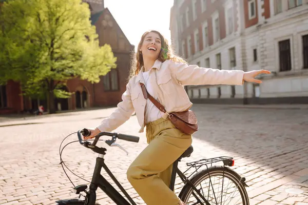 Güneşli şehir caddesinde yürüyüş yapan bisikletli neşeli bir kadın. Avrupa 'da bisikletle gezen bir turist. Aktif yaşam tarzı. Turizm, eğlence konsepti.