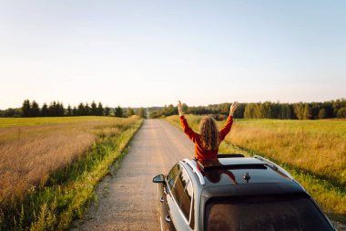 Arabasının camından sarkan neşeli kadın kendini özgür hissediyor. Arabayla seyahat eden genç bir kadın araba penceresinden yolculuğun tadını çıkarıyor. Macera ve ulaşım kavramı.