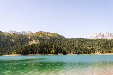 Dağlarla çevrili bir dağ gölü ve parlak mavi gökyüzü olan güzel doğal manzara. Göllü görkemli dağlar. Sükunet ve özgürlük kavramı.