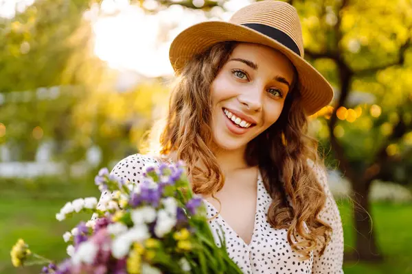Telefonu ve gür bir buket kır çiçeğiyle güzel bir kadın yeşil bir parkta günbatımının tadını çıkarıyor. Şapkalı ve telefonlu bir turist parkta dinlenirken sohbet ediyor ya da blog yazıyor..