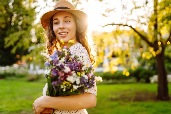 Telefonu ve gür bir buket kır çiçeğiyle güzel bir kadın yeşil bir parkta günbatımının tadını çıkarıyor. Şapkalı ve telefonlu bir turist parkta dinlenirken sohbet ediyor ya da blog yazıyor..