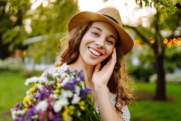Telefonu ve gür bir buket kır çiçeğiyle güzel bir kadın yeşil bir parkta günbatımının tadını çıkarıyor. Şapkalı ve telefonlu bir turist parkta dinlenirken sohbet ediyor ya da blog yazıyor..