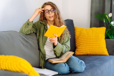 Sarı defterli gülümseyen kadının portresi rahat bir odada koltukta oturuyor. Genç kız öğrenci evdeki oturma odasında ders çalışıyor. Eğitim, dinlenme ve rahatlık kavramı.