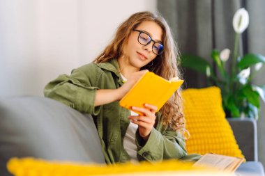 Sarı defterli gülümseyen kadının portresi rahat bir odada koltukta oturuyor. Genç kız öğrenci evdeki oturma odasında ders çalışıyor. Eğitim, dinlenme ve rahatlık kavramı.