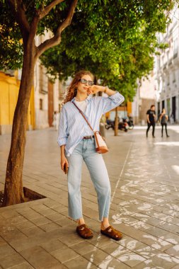 Güneşli Avrupa caddelerinde gezinen güzel turistler havanın tadını çıkarıyorlar. Mimariye bakan neşeli bir kadın. Aktif yaşam tarzı. Yürüme konsepti.