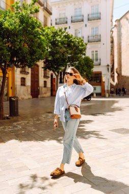 Güneşli Avrupa caddelerinde gezinen güzel turistler havanın tadını çıkarıyorlar. Mimariye bakan neşeli bir kadın. Aktif yaşam tarzı. Yürüme konsepti.