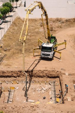 Valencia, İspanya - 20 Haziran 2025: Kentsel yerleşim alanına beton pompa kamyonu döken inşaat alanı, modern mimari ve geliştirme ilerlemelerini gözler önüne seriyor