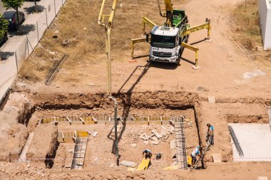 Valencia, İspanya - 20 Haziran 2025: Kentsel yerleşim alanına beton pompa kamyonu döken inşaat alanı, modern mimari ve geliştirme ilerlemelerini gözler önüne seriyor