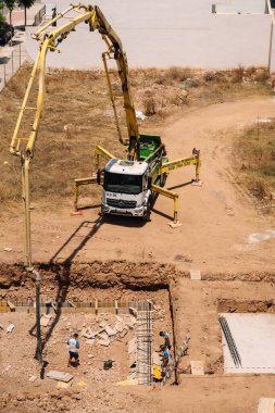 Valencia, İspanya - 20 Haziran 2025: Kentsel yerleşim alanına beton pompa kamyonu döken inşaat alanı, modern mimari ve geliştirme ilerlemelerini gözler önüne seriyor