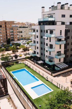 Valencia, İspanya - 20 Haziran 2025: Çağdaş apartman kompleksi şehir yaşam tarzını ve açık hava rahatlığını ön plana çıkaran bir yüzme havuzu ve yeşil bahçeye sahiptir.