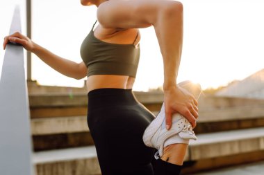 Spor yapan bir kadın gün batımında dışarıda egzersiz yapıyor. Spor giyimli güzel bir kadın spor sahasında antrenman yapıyor. Spor konsepti. Etkin yaşam biçimi.