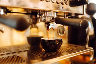 Espresso makinesi kahve yapar ve fincana sıcak kahve döker. Sıcak kahve dükkanı müşteriler için aromatik içecek hazırlar. İçki konsepti, kahve ve kahve dükkanı. Küçük işletme.