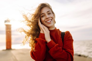 İskelede deniz fenerine hayran güzel bir kadının portresi. Tatlı kadın temiz havada özgürlüğü hissediyor. Özgürlük, doğa konsepti, rahat atmosfer.