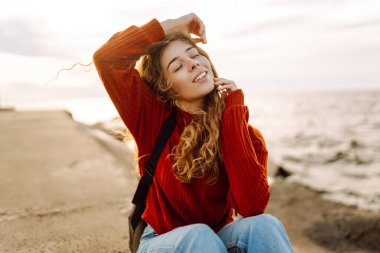 İskelede deniz fenerine hayran güzel bir kadının portresi. Tatlı kadın temiz havada özgürlüğü hissediyor. Özgürlük, doğa konsepti, rahat atmosfer.