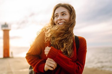 İskelede deniz fenerine hayran güzel bir kadının portresi. Tatlı kadın temiz havada özgürlüğü hissediyor. Özgürlük, doğa konsepti, rahat atmosfer.