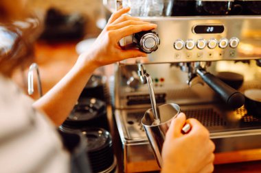 Önlüklü bir barmen barın arkasında kahve makinesiyle kahve hazırlar. Deneyimli bir barista sütünü köpürtür ve sıcak bir kafede taze espresso hazırlar. Tüketim konsepti, yemek servisi..