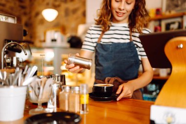 Önlüklü bir barmen barın arkasında kahve makinesiyle kahve hazırlar. Deneyimli bir barista sütünü köpürtür ve sıcak bir kafede taze espresso hazırlar. Tüketim konsepti, yemek servisi..