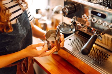 Önlüklü bir barmen barın arkasında kahve makinesiyle kahve hazırlar. Deneyimli bir barista sütünü köpürtür ve sıcak bir kafede taze espresso hazırlar. Tüketim konsepti, yemek servisi..