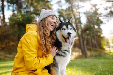 Parlak bir yağmurluk ve şirin bir köpekle mutlu bir kadın güneşli bir günde yeşil bir çimenlikte yürüyor. Sevgili evcil hayvanıyla birlikte dışarıda vakit geçiren genç bir kadın. Arkadaşlık kavramı, eğlence..