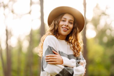 Yoğun bir ormanda, güneş ışınları altında neşeli bir kadının portresi. Parkta yürüyüş yapan güzel bir kadın. Hafta sonu ve eğlence konsepti. Etkin yaşam biçimi.