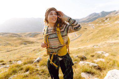 Renkli sırt çantalı kadın yürüyüşçü görkemli dağların arasında özgürlüğünü hissediyor. Genç bayan gezgin dağ manzarasının tadını çıkarıyor. Doğa ve özgürlük kavramı.