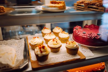 Taze ve lezzetli tatlılar bu sıcak fırının cam kubbesinin altında cezbedici. Kahve dükkanında mis kokulu tarçınlı çörekler, kekler ve kekler ile sıcak bir atmosfer. Tatlı ve yemek konsepti.