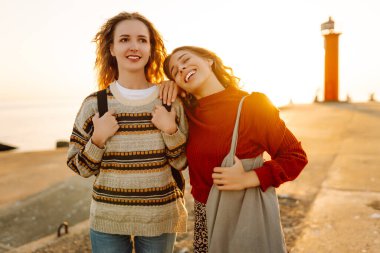 İki bayan arkadaş deniz fenerinin arka planında eğleniyor ve rıhtımda yürüyorlar. Güzel kadınlar gün batımını ve birlikte dışarıda vakit geçirmeyi seviyorlar. Arkadaşlık kavramı, yürüme.