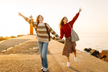 İki bayan arkadaş deniz fenerinin arka planında eğleniyor ve rıhtımda yürüyorlar. Güzel kadınlar gün batımını ve birlikte dışarıda vakit geçirmeyi seviyorlar. Arkadaşlık kavramı, yürüme.