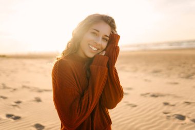 Şapkalı neşeli kadın güneşli sahilde eğleniyor ve yürüyor. Özgürlüğü hisseden ve deniz manzarasının tadını çıkaran güzel bir kadın. Özgürlük, rahatlama konsepti. Yaşam biçimi.