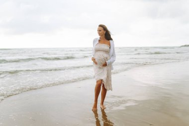 Bulutlu bir günde, elbiseli hamile bir kadın deniz kıyısında yürüyor. Çocuk bekleyen güzel bir kadın dışarıda doğanın tadını çıkarıyor. Özgürlük kavramı, rahatlama..