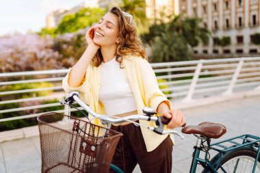 Neşeli bir turist şehrin güneşli caddelerinde bisiklet sürüyor. Güneş gözlüklü güzel bir kadın gün batımında bisiklet sürmekten hoşlanır. Turizm kavramı, eko taşımacılık.