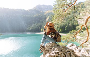 Sırt çantalı bir bayan yürüyüşçü güneşli bir günde bir gölün yakınındaki dağlık alanı keşfeder. Genç bayan gezgin dağ gölünün ve yoğun bir ormanla çevrili maceranın tadını çıkarıyor. Özgürlük kavramı, tatil.