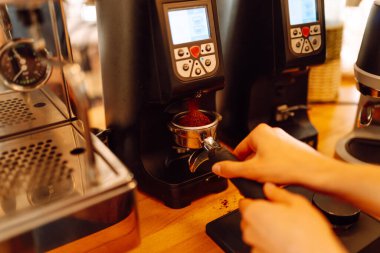 Deneyimli bir barista modern bir espresso makinesinde aromatik kahve hazırlar. Süt köpürten bir kadının elleri, sıcak bir kahve dükkanında espresso hazırlıyor. Küçük işletme konsepti, içkiler.
