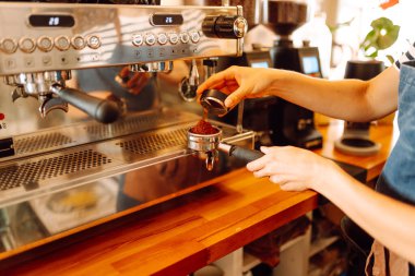 Deneyimli bir barista modern bir espresso makinesinde aromatik kahve hazırlar. Süt köpürten bir kadının elleri, sıcak bir kahve dükkanında espresso hazırlıyor. Küçük işletme konsepti, içkiler.