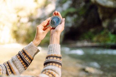 Dağın eteklerinde pusula tutan kadın yürüyüşçünün arka görüntüsü. Yürüyüş yapan güzel bir kadın yön bulmak için pusulaya bakıyor, araziyi keşfediyor. Macera konsepti, yürüyüş. Etkin yaşam biçimi.
