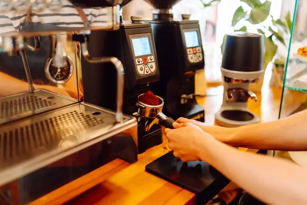 Deneyimli bir barista modern bir espresso makinesinde aromatik kahve hazırlar. Süt köpürten bir kadının elleri, sıcak bir kahve dükkanında espresso hazırlıyor. Küçük işletme konsepti, içkiler.