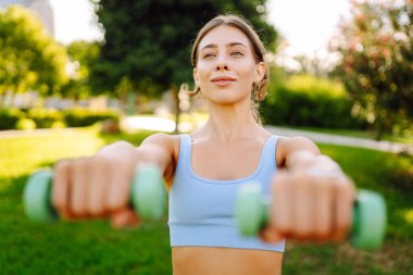 A young woman in activewear exercises in a sunny park. An athletic woman performs exercises on a pink yoga mat on a green lawn. Concepts: sports, outdoors, active lifestyle.