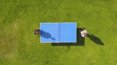 Hava manzaralı insanlar dışarıda pinpon oynuyorlar. Yeşil çimlerin üzerinde masa tenisi oynayan iki çocuk (pingpong). Hava manzaralı açık hava sporu