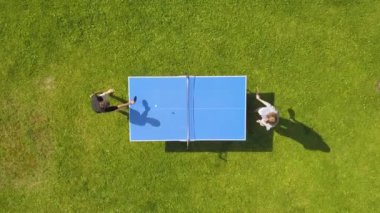 Hava manzaralı insanlar dışarıda pinpon oynuyorlar. Yeşil çimlerin üzerinde masa tenisi oynayan iki çocuk (pingpong). Hava manzaralı açık hava sporu