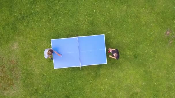 屋外でピンポンマッチをプレイする空中ビュー トップビュー 緑の芝生で卓球 ピンポン をする2人の少年 アリアルビューアウトドアスポーツ — ストック動画