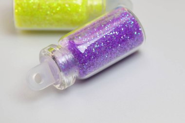 Beyaz arka planda izole edilmiş küçük bir cam şişede mor ya da mor parıltılar. Parlak cam bir şişeye yakın çekim. Hayat tecrübesi. Mor ya da mor parıltılar izole.