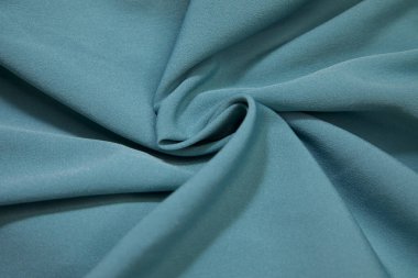 Turquoise fabric background. Turquoise cloth waves background texture. Turquoise fabric cloth textile material.