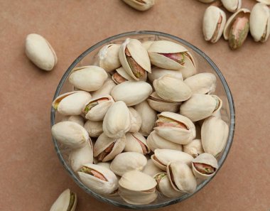 Fıstıklar kahverengi arka planda kasede. Yemek konsepti. Seçici odak.